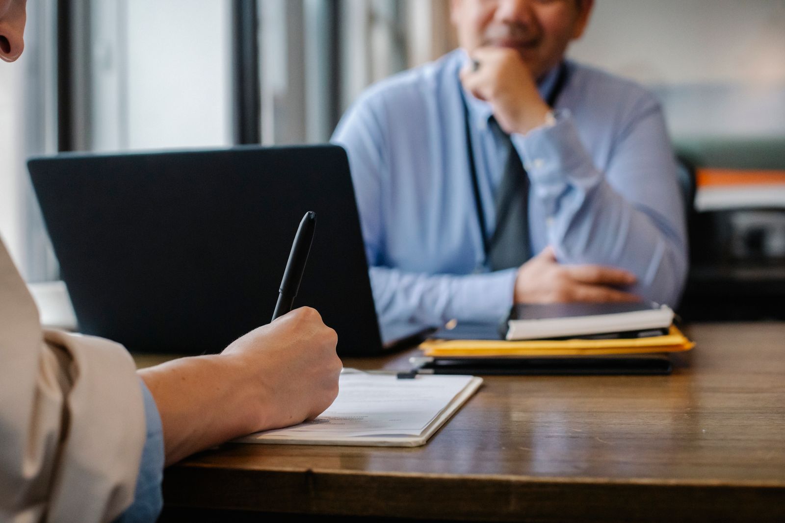 Two people reviewing an agreement together across a table, supported by their collaborative team.